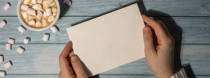 Cropped hands of woman holding book on table