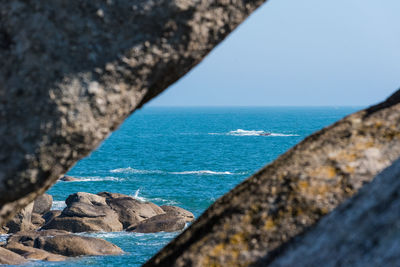 Rocks by sea against blue sky