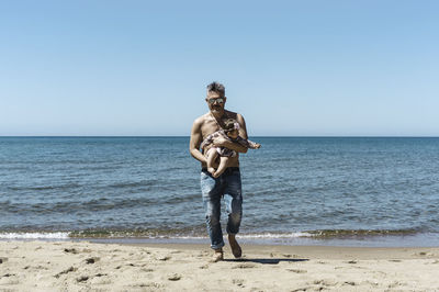 Full length of man standing on beach against clear sky