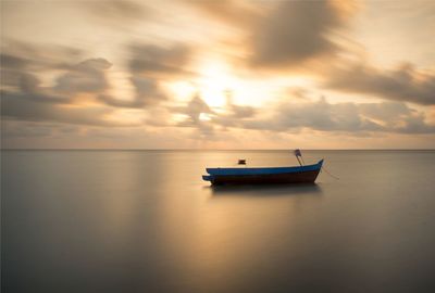 Boat in sea against sunset sky
