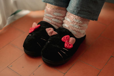 Low section of person wearing canvas shoes on tiled floor