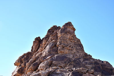 Low angle view of rock formation against clear blue sky