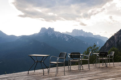 Empty chairs and tables against mountains