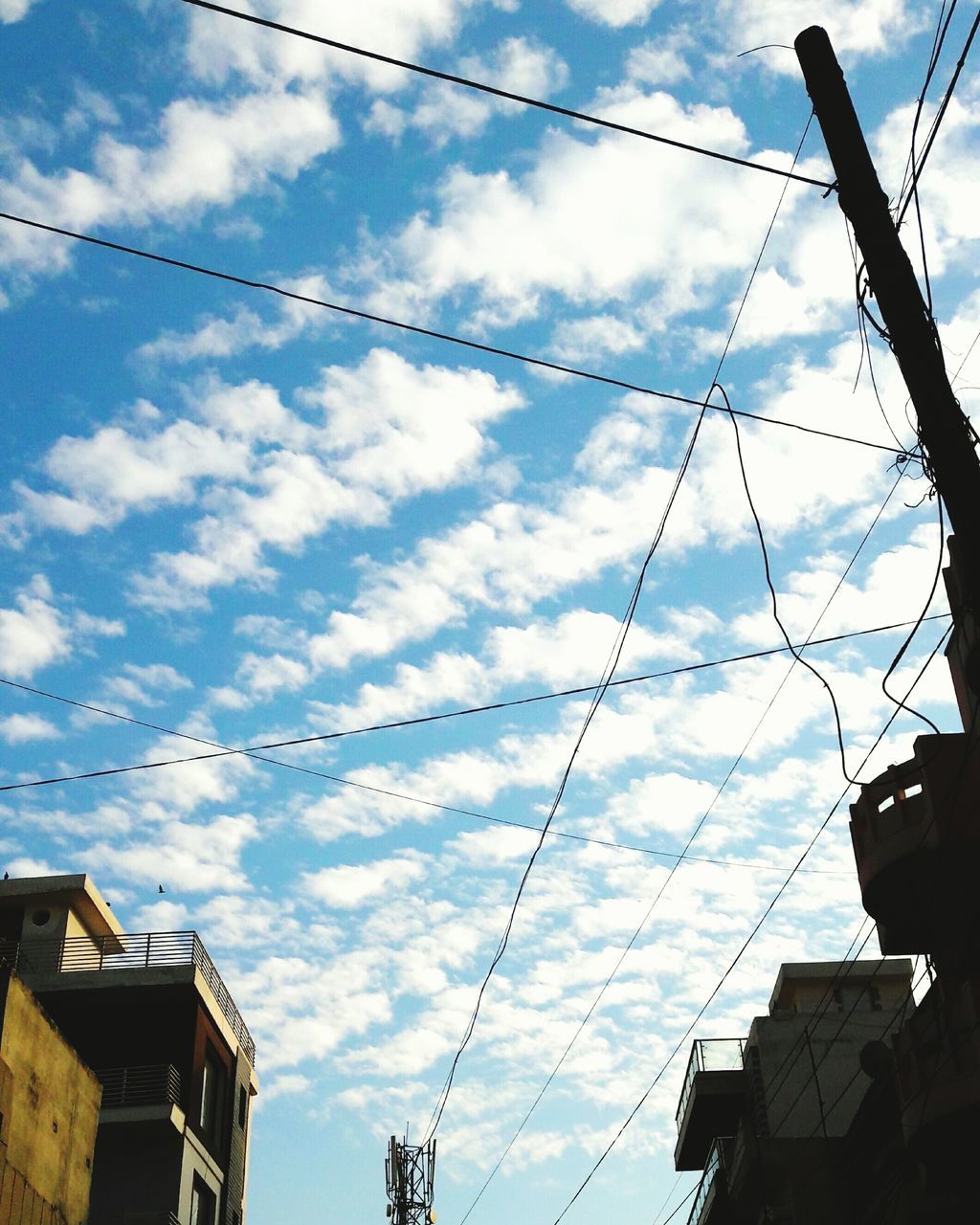 low angle view, sky, building exterior, architecture, power line, built structure, cable, cloud - sky, cloud, electricity pylon, cloudy, electricity, power supply, connection, residential structure, house, residential building, building, outdoors, day