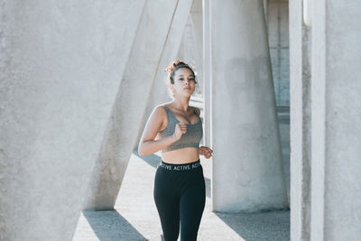 Female athlete running between column