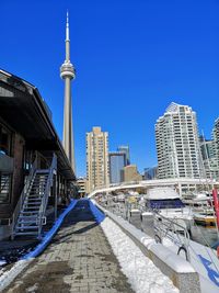 View of cn tower and modern buildings against blue sky