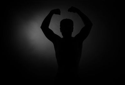 Silhouette man standing against black background