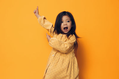 Portrait of young woman standing against yellow background