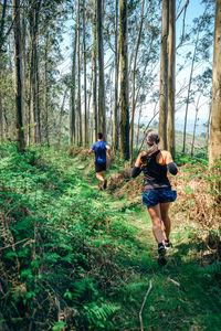 Rear view of man and woman walking in forest