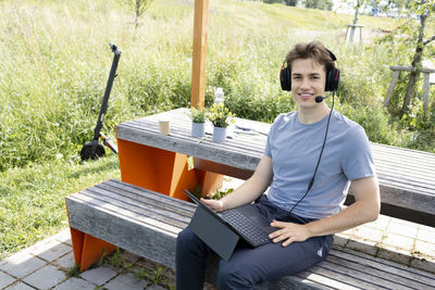 Young man using mobile phone while sitting on bench