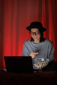 Portrait of woman using laptop while sitting on sofa at home