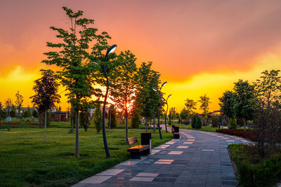 People walking on footpath against sky during sunset