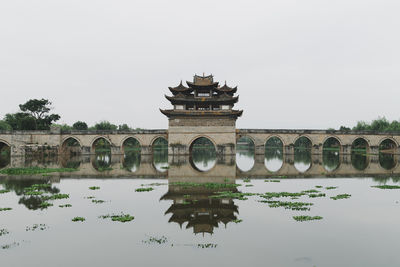 Reflection of building in lake against clear sky