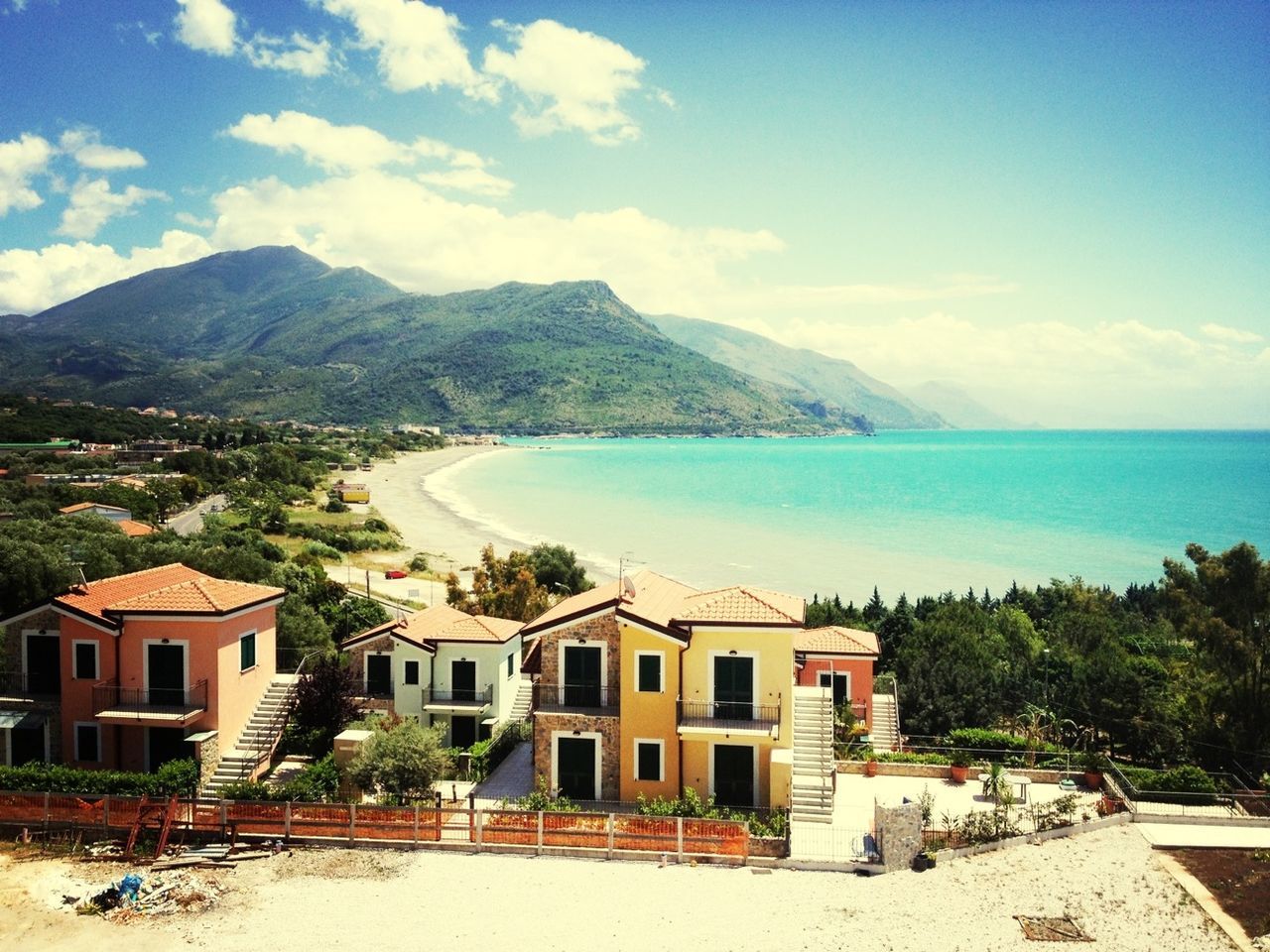 sea, sky, built structure, architecture, mountain, building exterior, water, beach, blue, house, scenics, tranquil scene, beauty in nature, horizon over water, nature, tranquility, cloud - sky, cloud, shore, tree