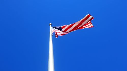 Low angle view of flag flags against clear blue sky