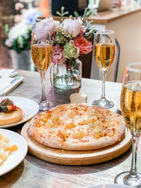 Pizza and champagne glasses on wooden table 