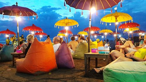 People relaxing at beach against sky