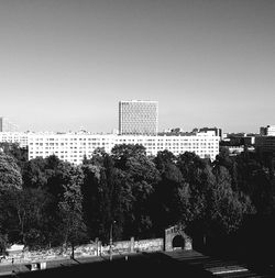 Trees and cityscape against clear sky