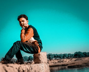 Young man looking away against blue sky