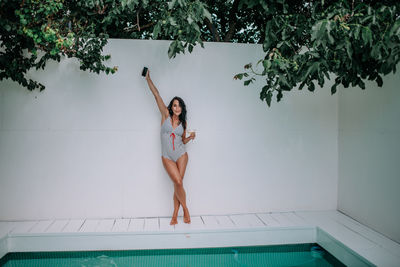 Full length of woman sitting against wall