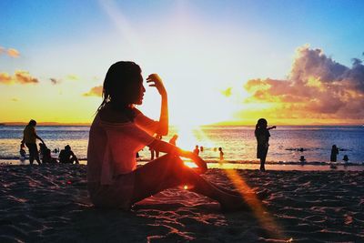 People on beach against sky during sunset