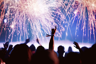 Crowd at music concert against firework during night