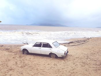 Vintage car on beach against sky