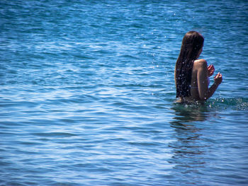 Rear view of woman with long hair swimming in sea during summer