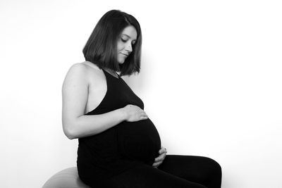 Young woman sitting against white background