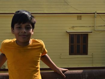 Portrait of boy standing against built structure