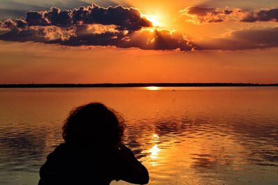 Rear view of silhouette woman against orange sky during sunset