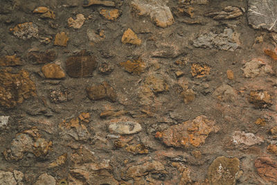 Horizontal stoned rock cobble stone wall with mortar for a textured background abstract material