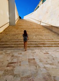 Rear view of woman walking towards steps