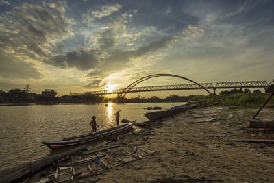 Bridge over river against sky during sunset