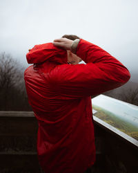 Rear view of man standing by railing against sky