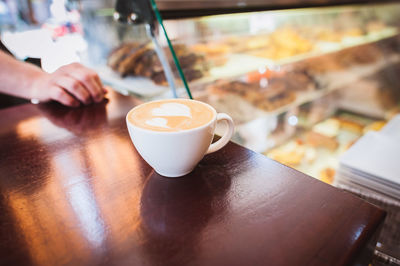 Cropped hand of man by coffee on table at store