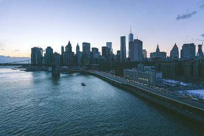 High angle view of brooklyn bridge over east river by modern buildings at sunset