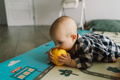 Cute baby girl playing with playing with an orange on a play mat.