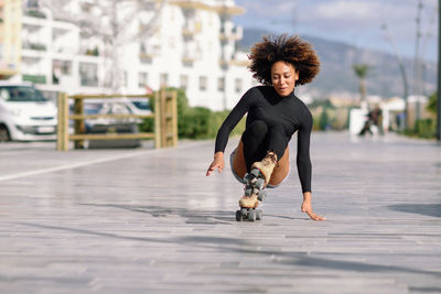 Young woman roller skating on sidewalk in city