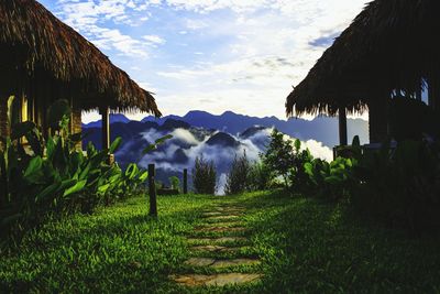 Thatched roof houses against mountain during foggy weather