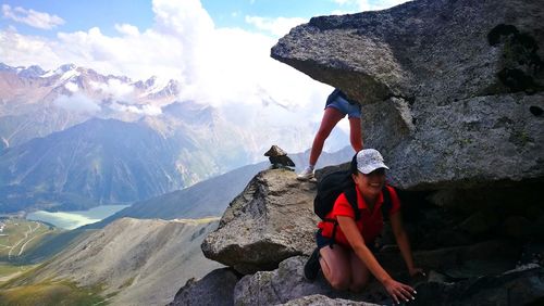 People sitting on rock against mountains