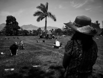 Rear view of woman looking towards people at cemetery