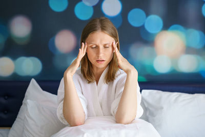 Young woman sitting on bed