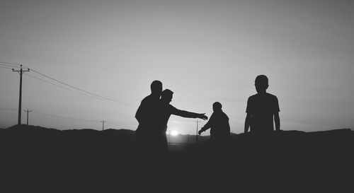 Silhouette people on landscape against clear sky