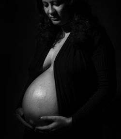 Woman looking away while standing against black background