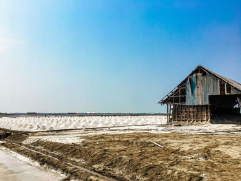 Abandoned house by sea against clear blue sky