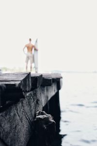 Close-up of men standing by sea against sky