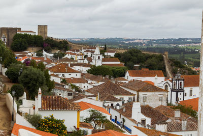 High angle view of houses in medieval town of obidos with castle against sky