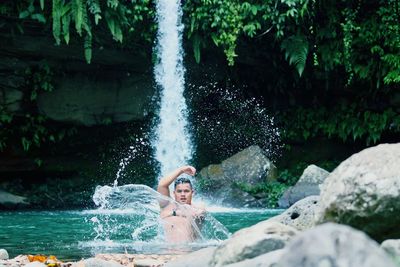 Portrait of man standing below waterfall