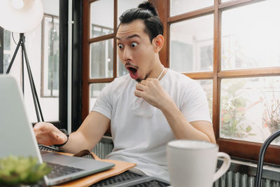 Young man using mobile phone while sitting on table